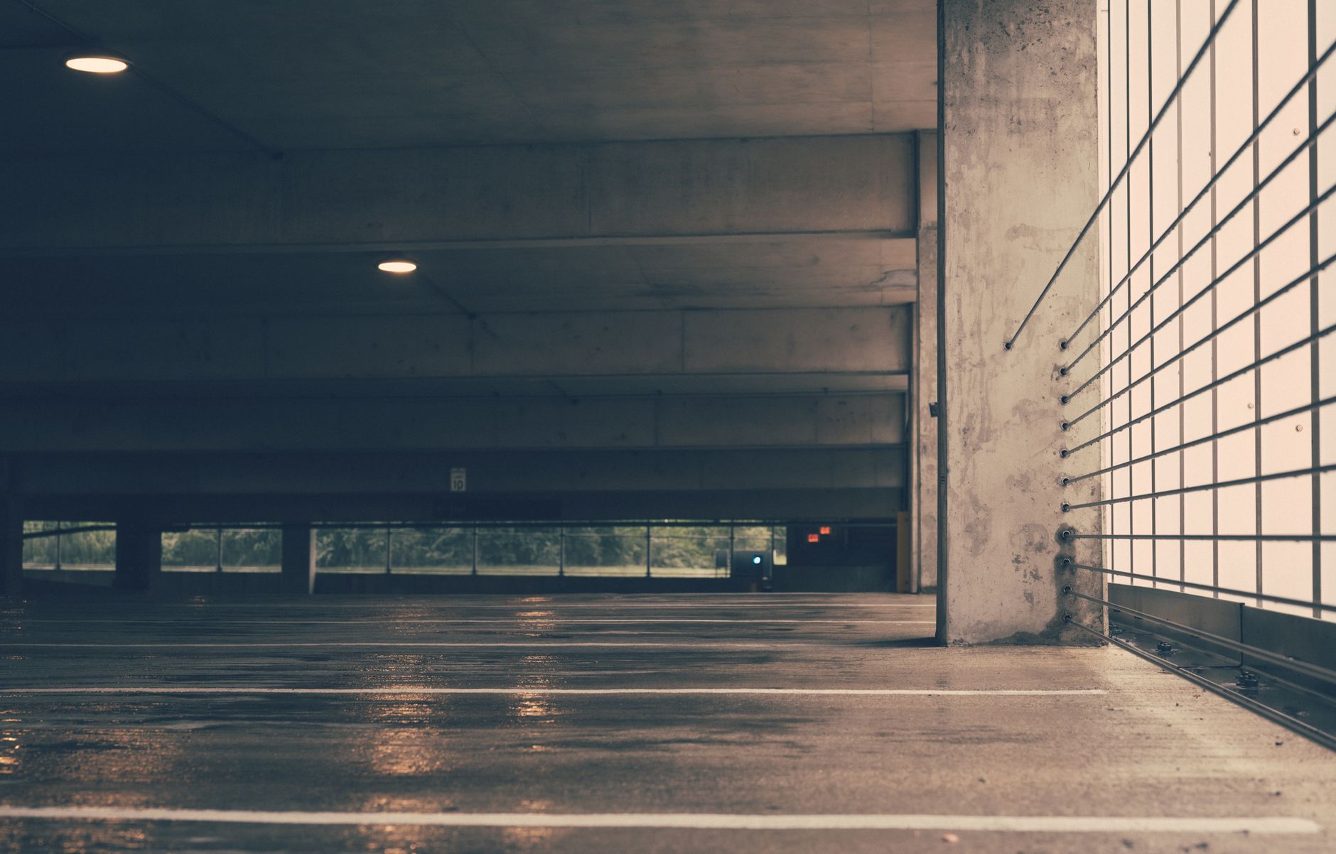 Deserted indoor parking garage with industrial design and wet concrete floor creating a moody ambiance