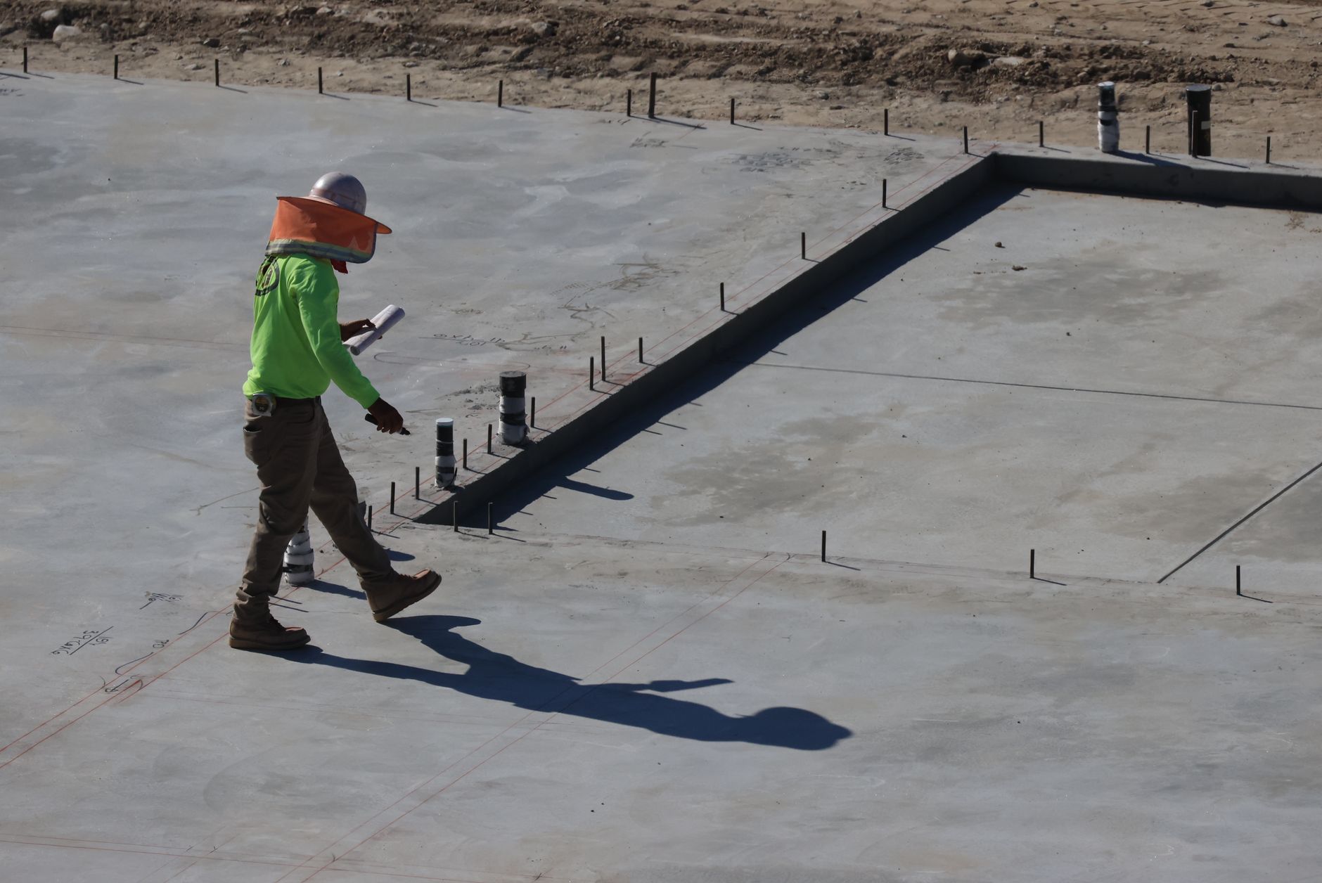 Engineer inspecting concrete slab at construction site in daylight