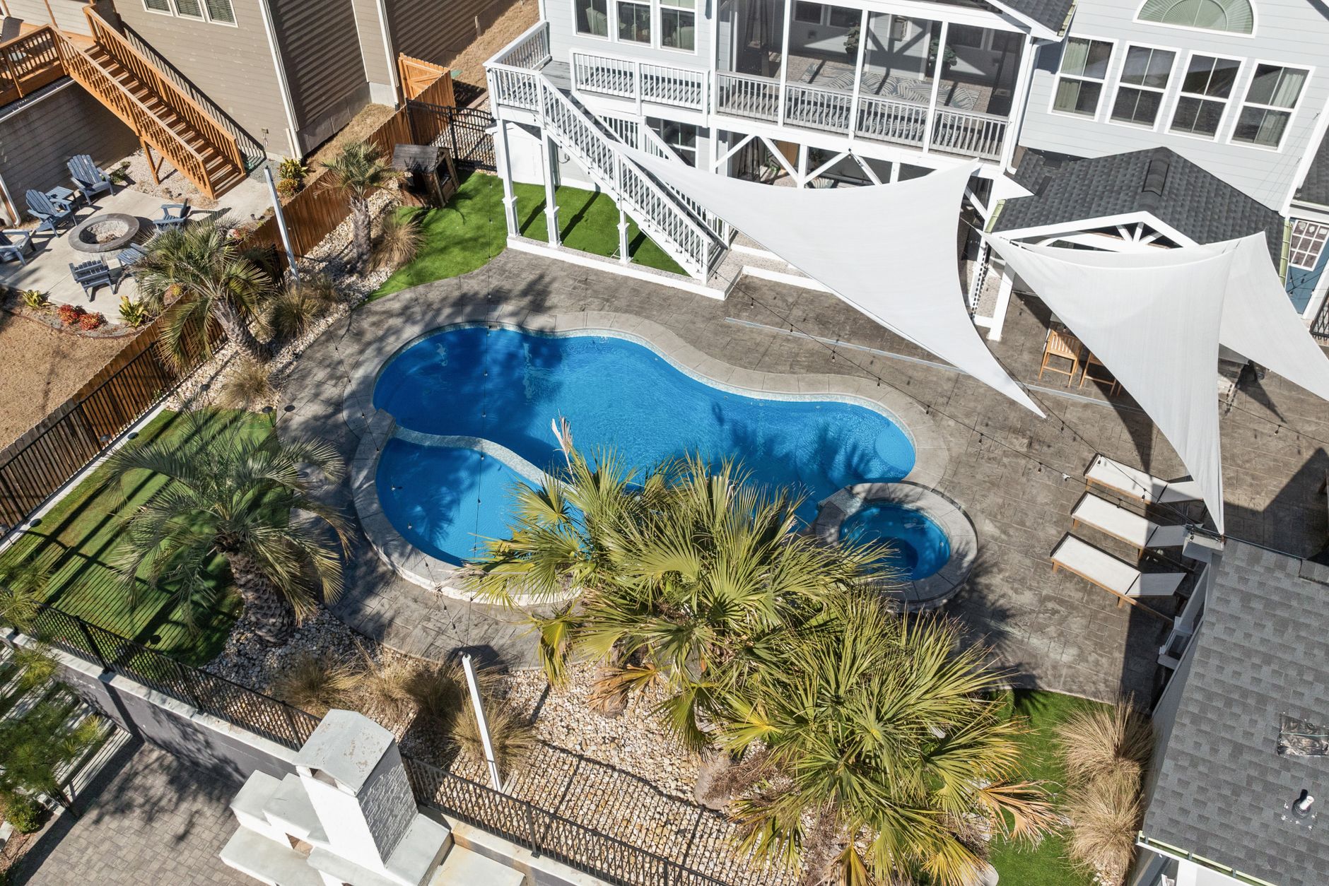 An aerial view of a modern backyard with a kidney-shaped swimming pool and surrounding patio