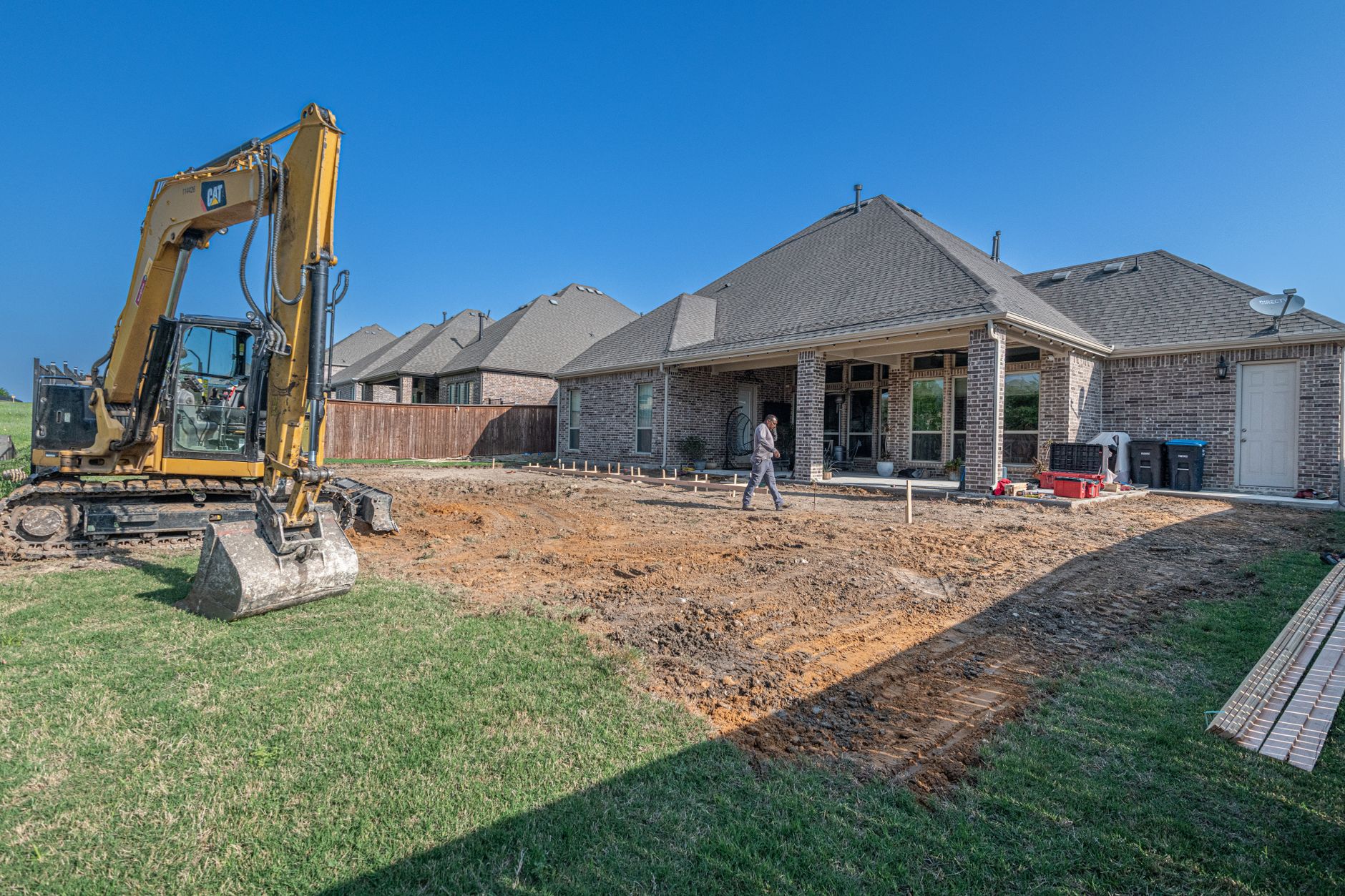 A construction site for a new patio in a Texas backyard with heavy machinery
