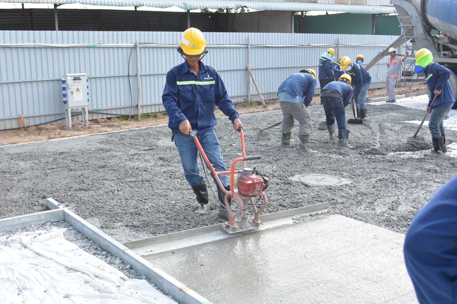 Team of workers smoothing and leveling wet concrete at a construction site