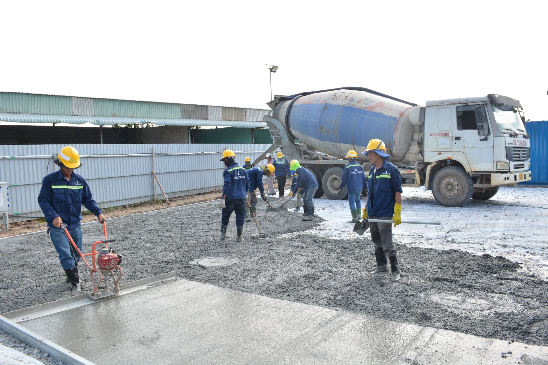 Team of workers pouring cement from a mixer truck on a construction site, ensuring proper leveling