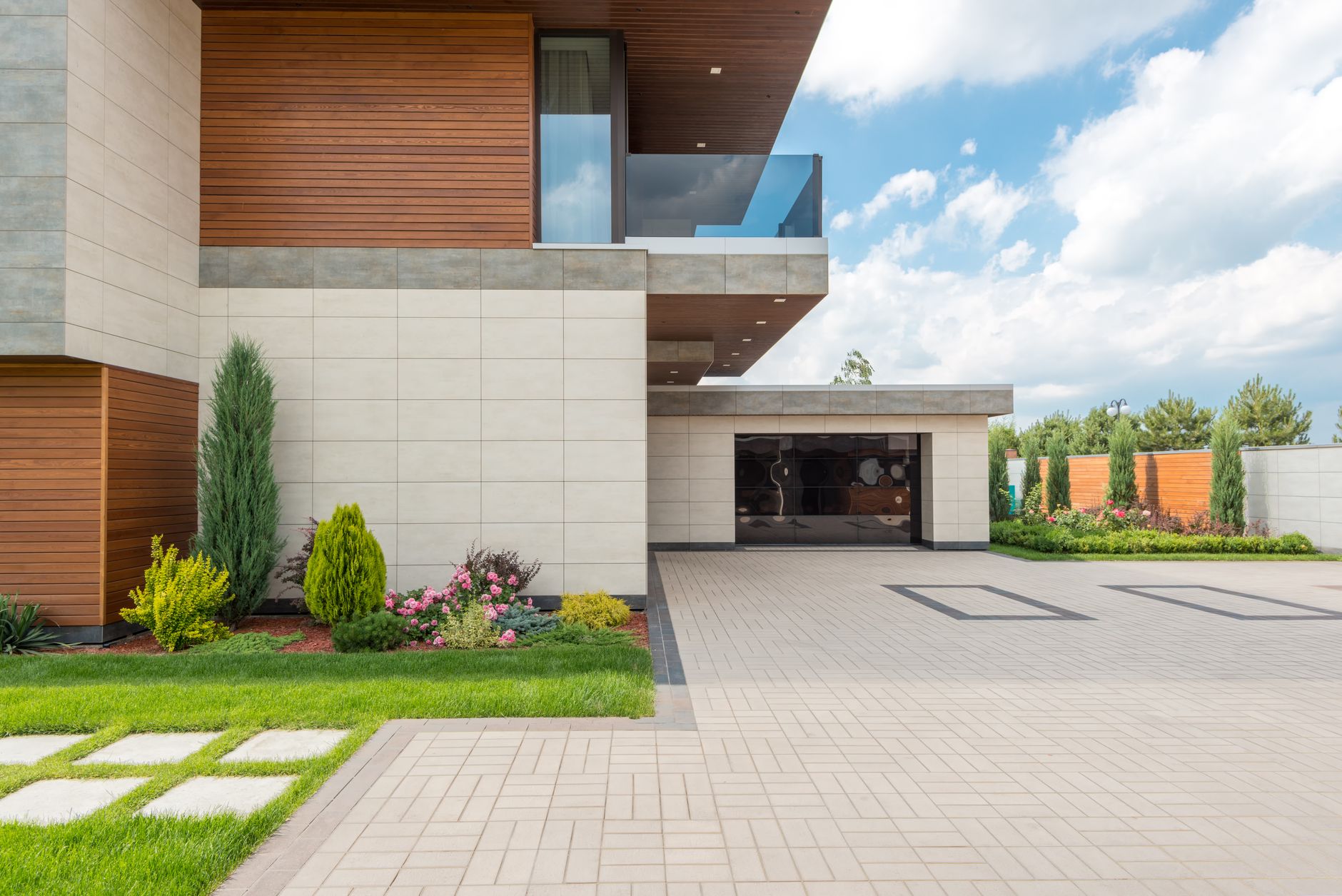 A modern minimalist house with a spacious driveway, landscaped garden, and clear blue sky