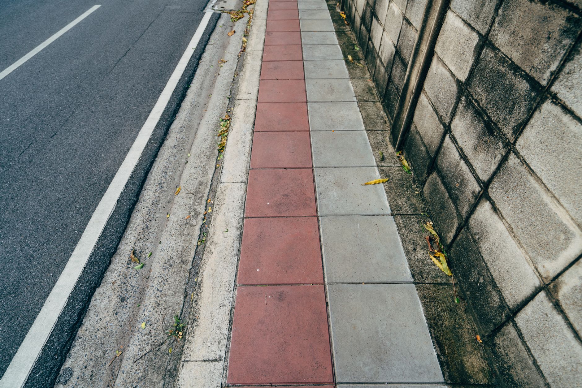 View of a colorful urban sidewalk with a textured wall beside it.